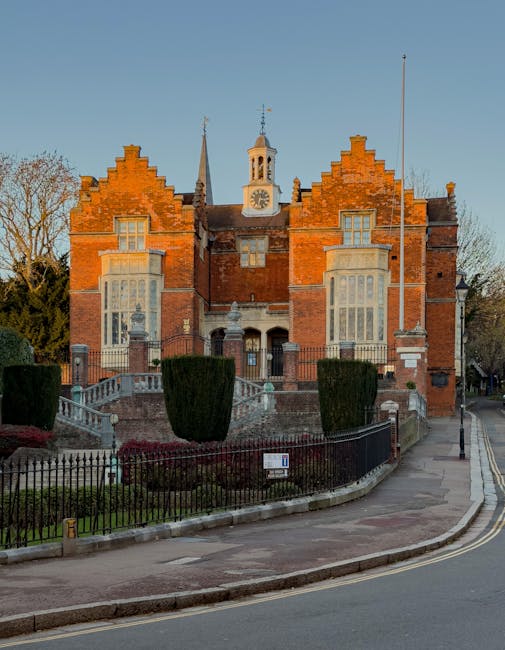 The image depicts a street scene in front of a historic stone church with a tall, pointed spire topped with a greenish copper roof. Nearby, there are brick buildings with traditional architecture and 